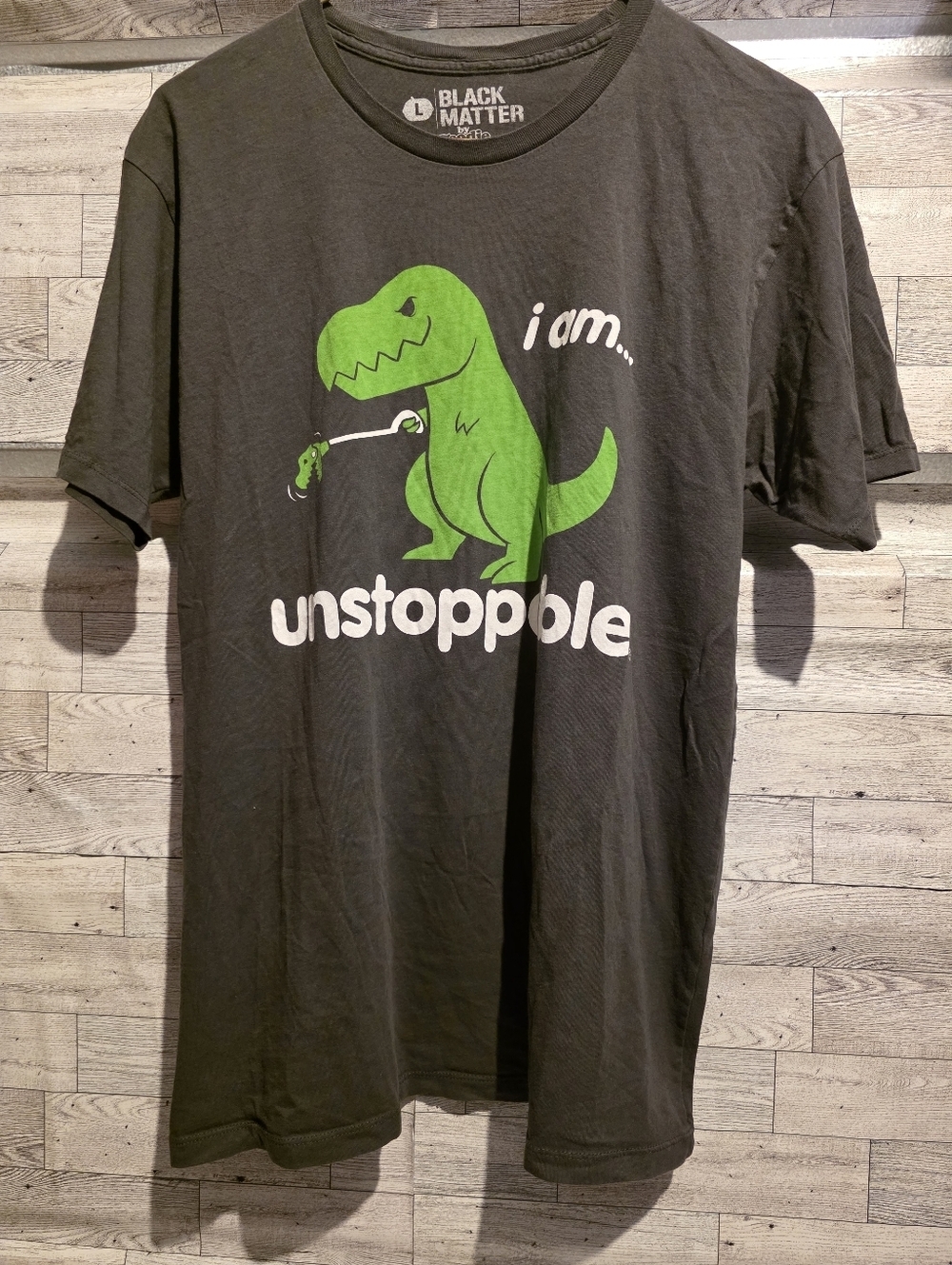 Black Matter black tee with bright green dinosaur graphic